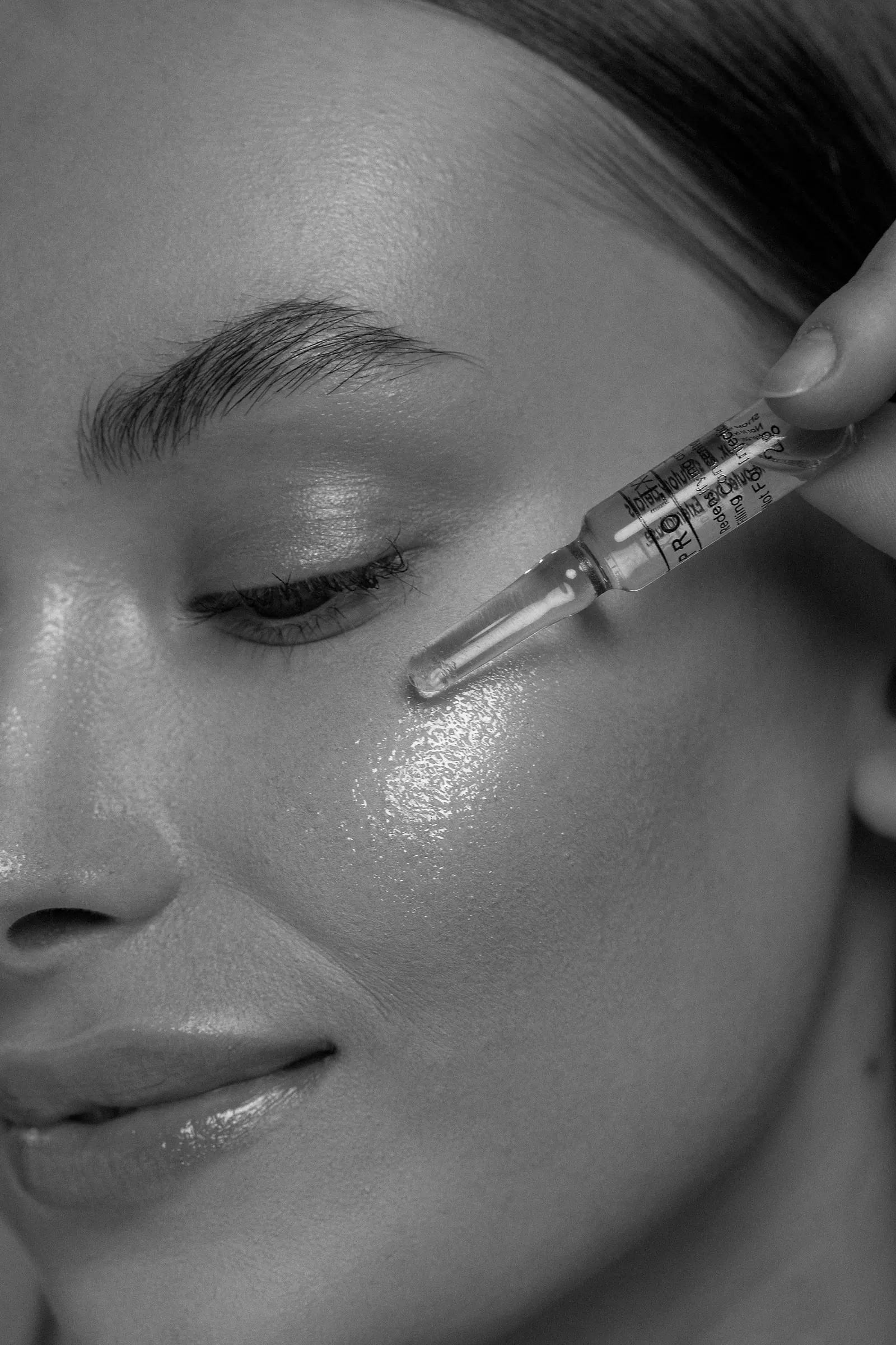 A serum ampoule held at the cheekbone